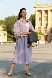 Beautiful young woman with stylish backpack on city street