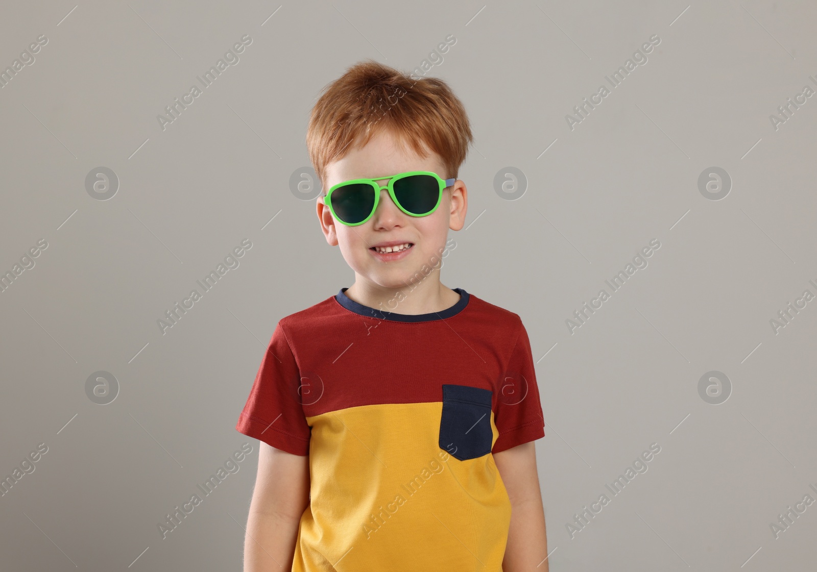 Photo of Cute little boy with sunglasses on light grey background