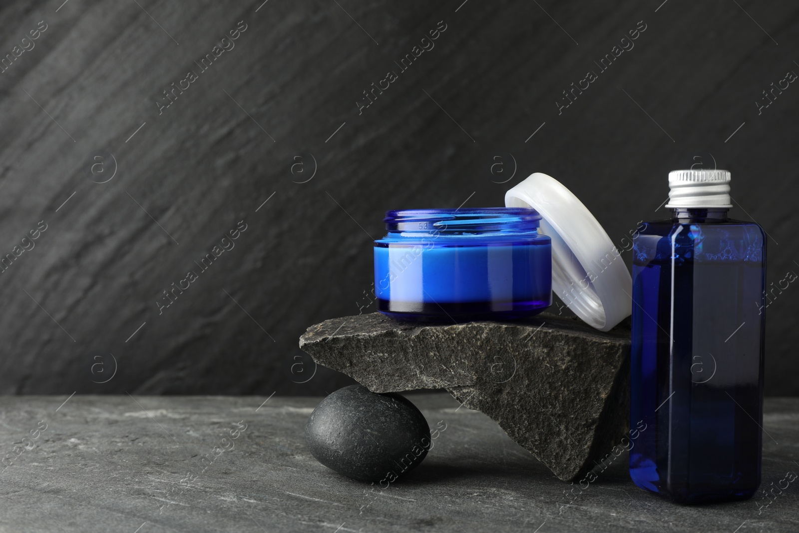 Photo of Cosmetic products and stones on grey background. Space for text