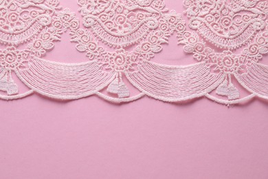 White lace on pink background, top view. Space for text