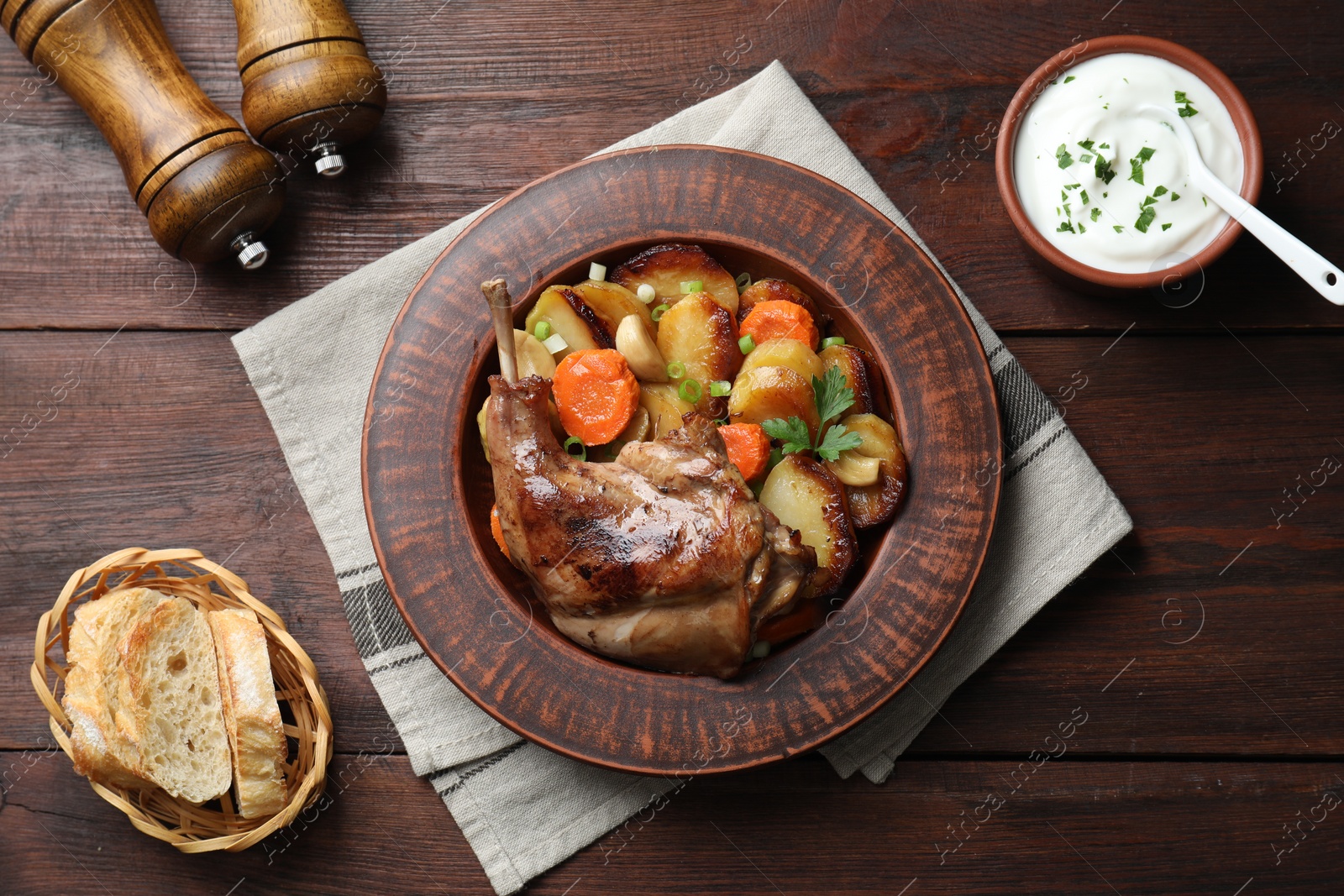 Photo of Tasty cooked rabbit meat with vegetables served on wooden table, flat lay