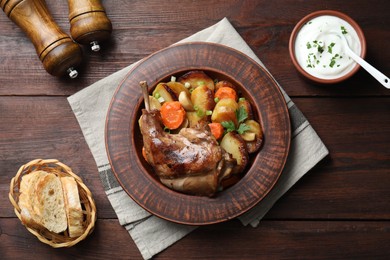 Tasty cooked rabbit meat with vegetables served on wooden table, flat lay