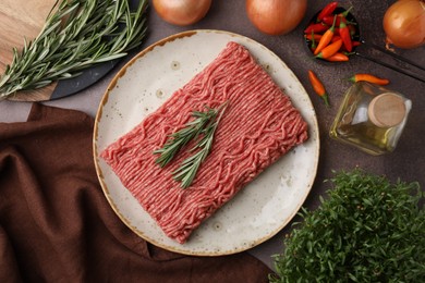 Flat lay composition with fresh raw ground meat, herbs and products on brown textured table