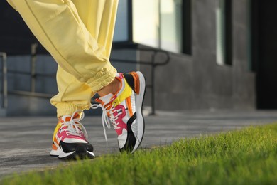 Woman wearing stylish sneakers outdoors, closeup. Space for text