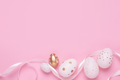 Many painted Easter eggs and ribbon on pink background, flat lay. Space for text