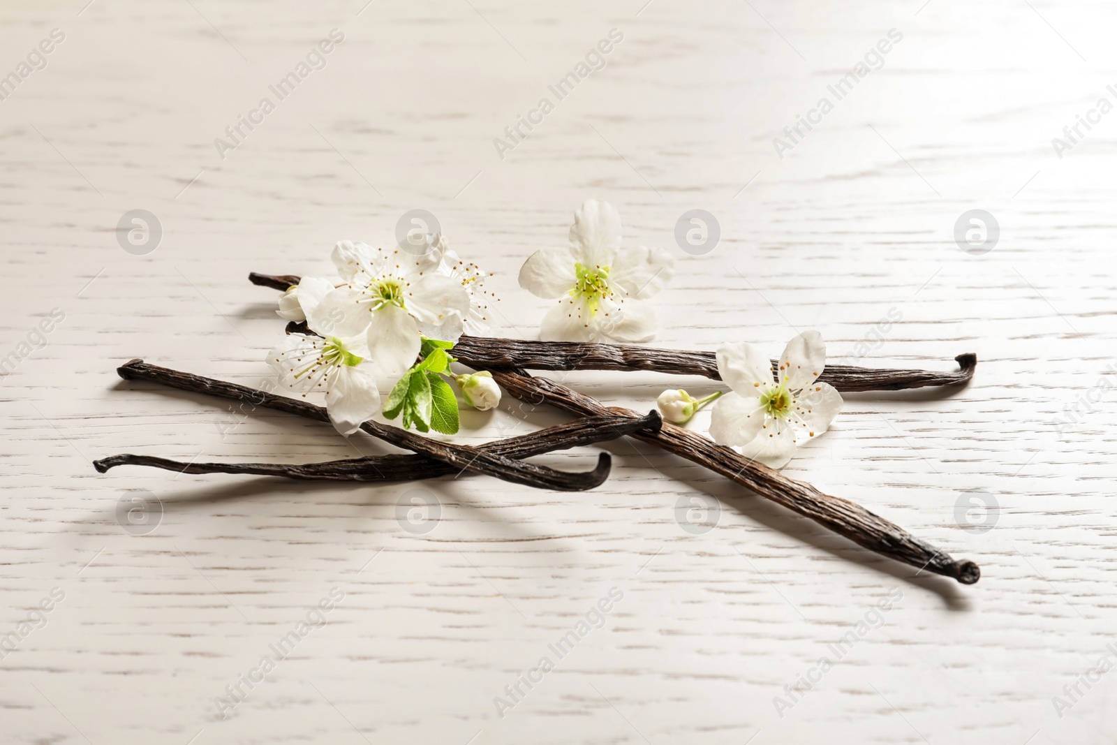 Photo of Vanilla sticks and flowers on wooden background