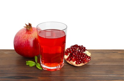 Photo of Refreshing pomegranate juice in glass, leaves and fruits on wooden table against white background