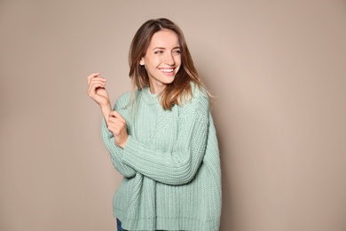 Image of Happy young woman wearing warm sweater on beige background