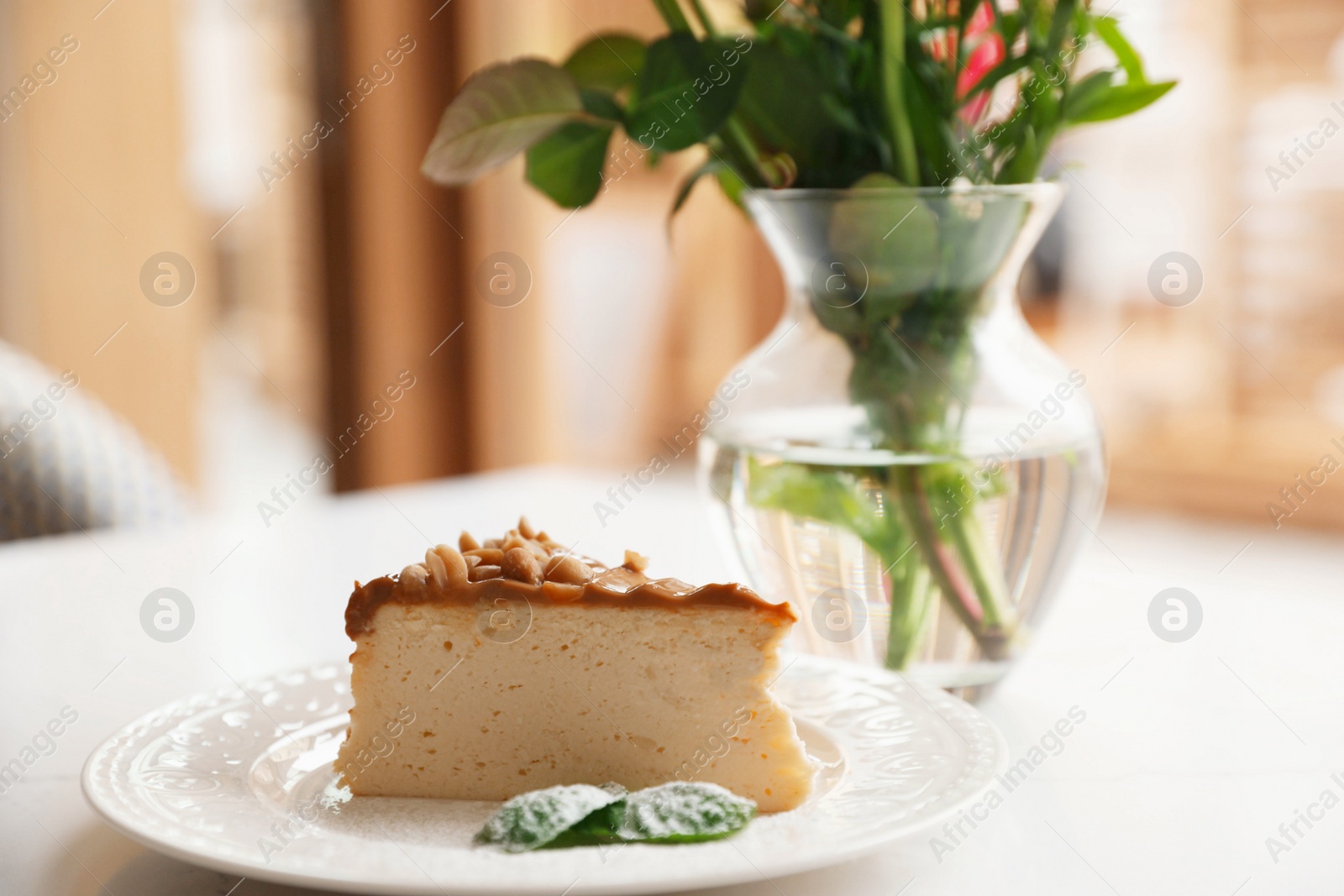 Photo of Tasty dessert and vase with flowers on white table indoors