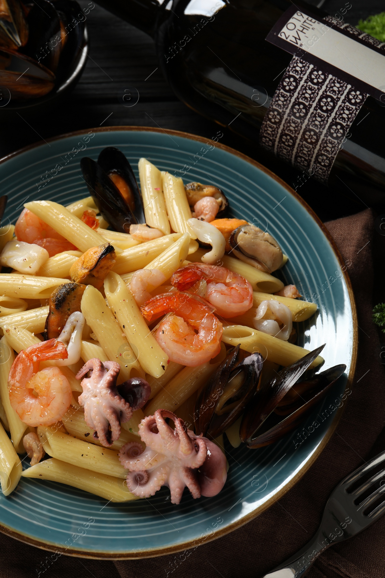Photo of Delicious pasta with seafood served on black table, flat lay