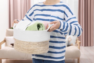 Photo of Woman with basket full of laundry at home, closeup