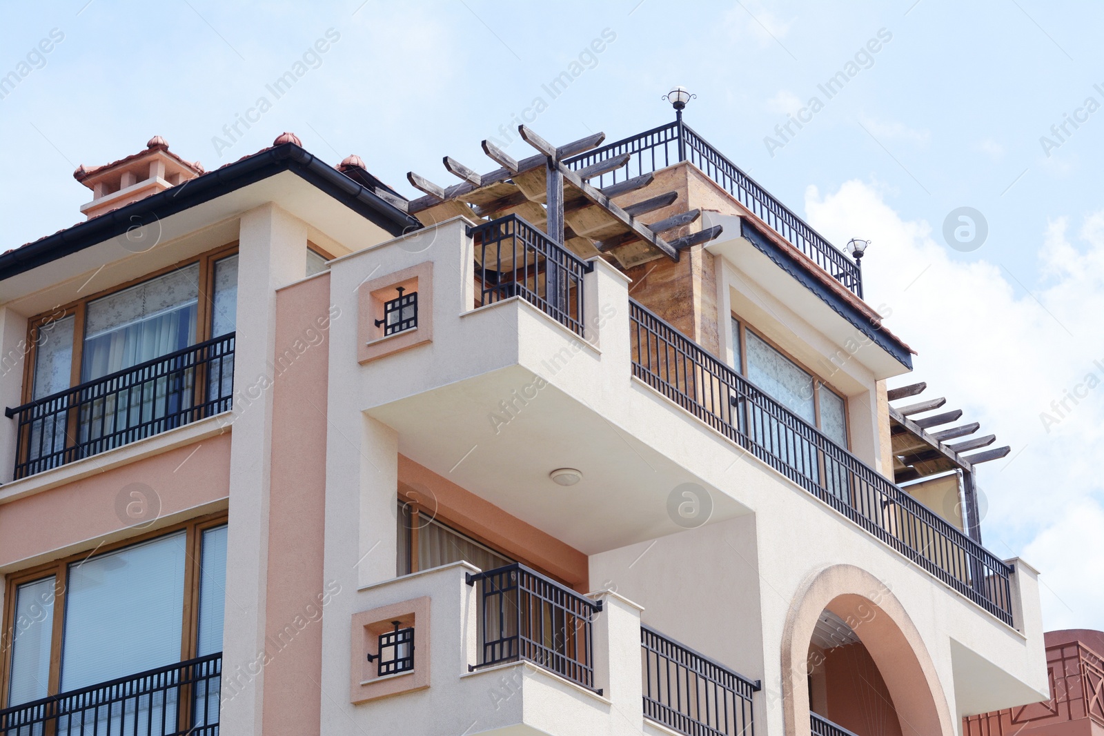 Photo of Exterior of residential building with balconies against blue sky, low angle view