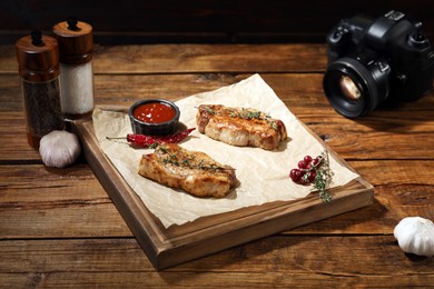 Food stylist. Beautiful composition with meat medallions and professional camera on wooden table in studio