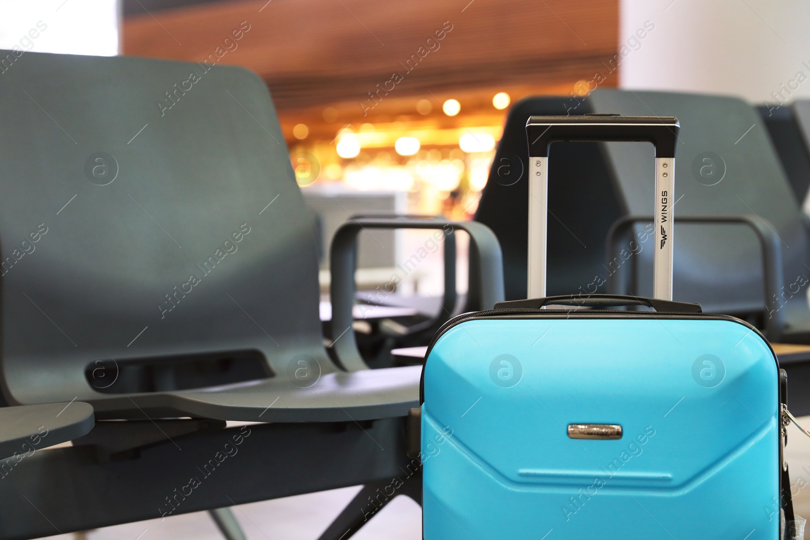 Photo of ISTANBUL, TURKEY - AUGUST 6, 2019: Bright modern suitcase near bench in airport