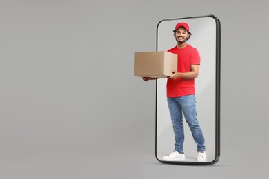 Image of Courier with parcel walking out from huge smartphone on grey background. Delivery service. Space for text