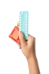 Photo of Young woman holding birth control pills and condoms on white background, closeup. Safe sex concept