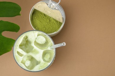 Glass of tasty iced matcha latte, powder and leaf on light brown background, flat lay. Space for text