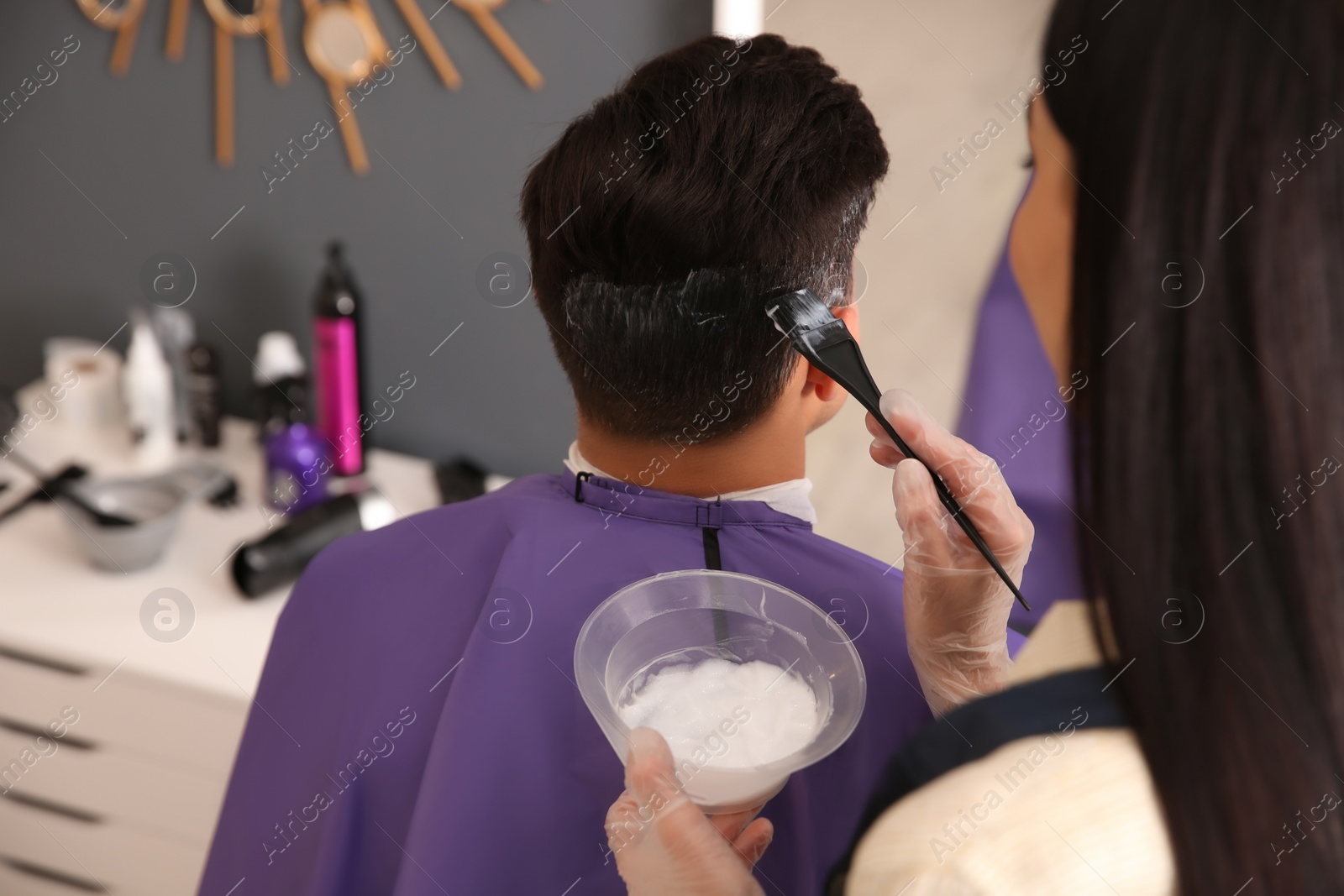 Photo of Professional hairdresser dying hair in beauty salon, back view