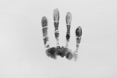 Photo of Print of hand and fingers on white background, top view. Criminal investigation