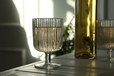 Alcohol drink in glasses and bottle on wooden table indoors, closeup