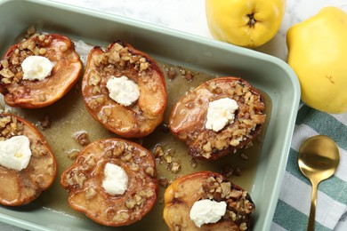 Tasty baked quinces with nuts and cream cheese in dish on table, flat lay