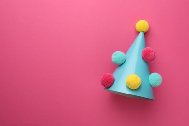 Photo of One light blue party hat with pompoms on pink background, top view. Space for text