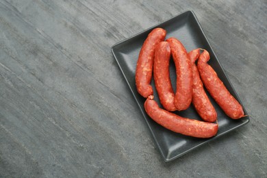 Photo of Tasty sausages in plate on black table, top view with space for text. Meat product.