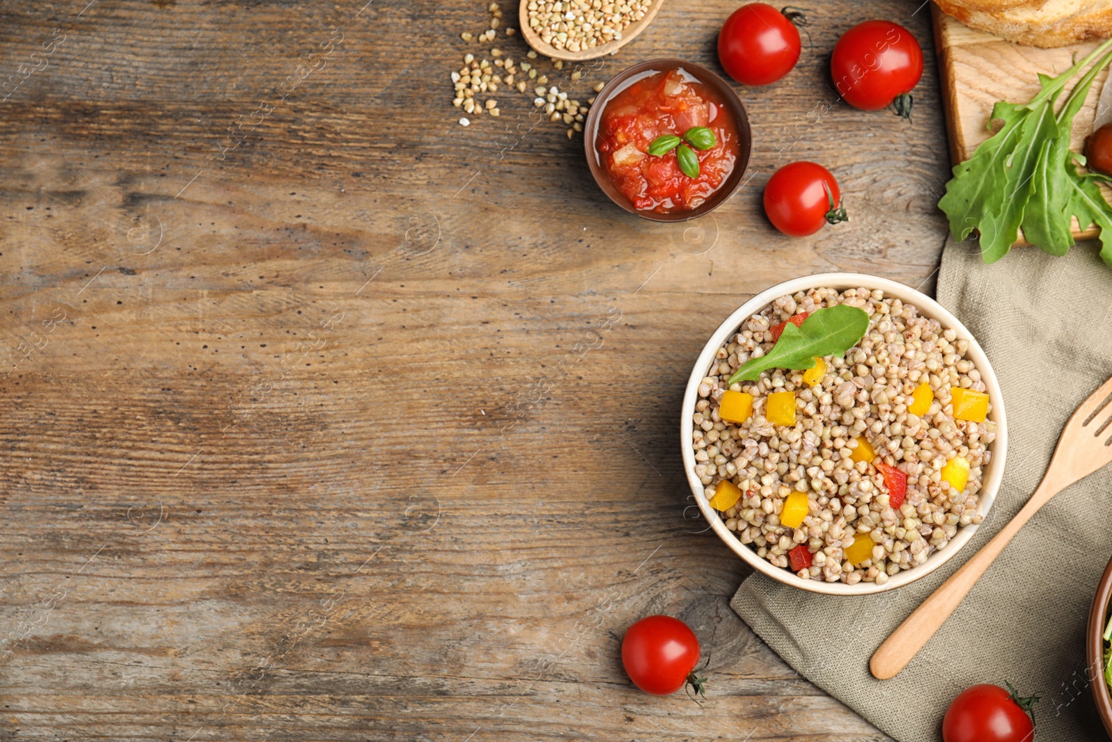 Photo of Tasty buckwheat porridge with vegetables on wooden table, flat lay. Space for text