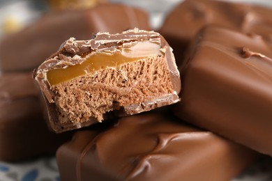 Photo of Delicious chocolate candy bars with caramel as background, closeup