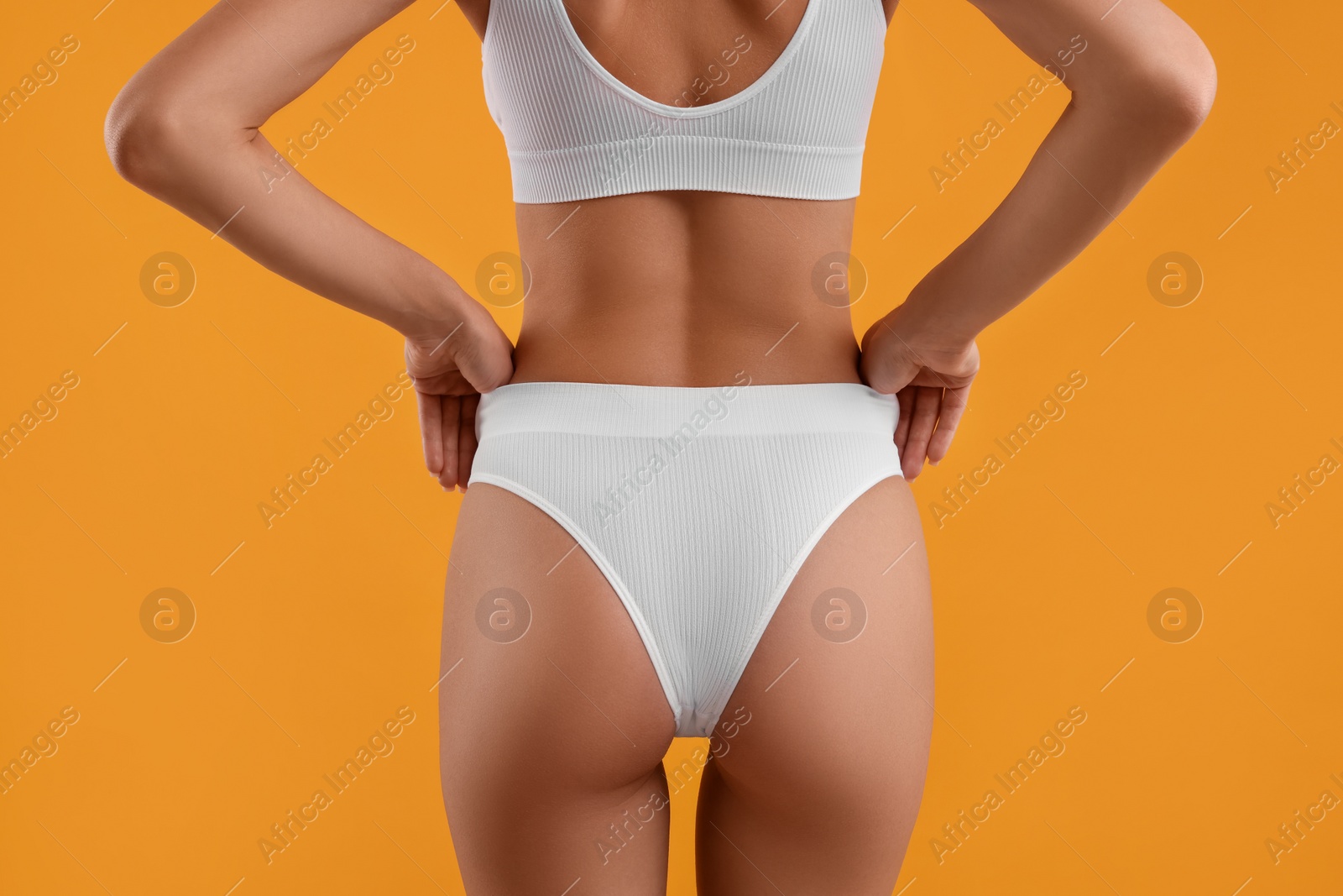 Photo of Young woman in stylish white bikini on orange background, closeup