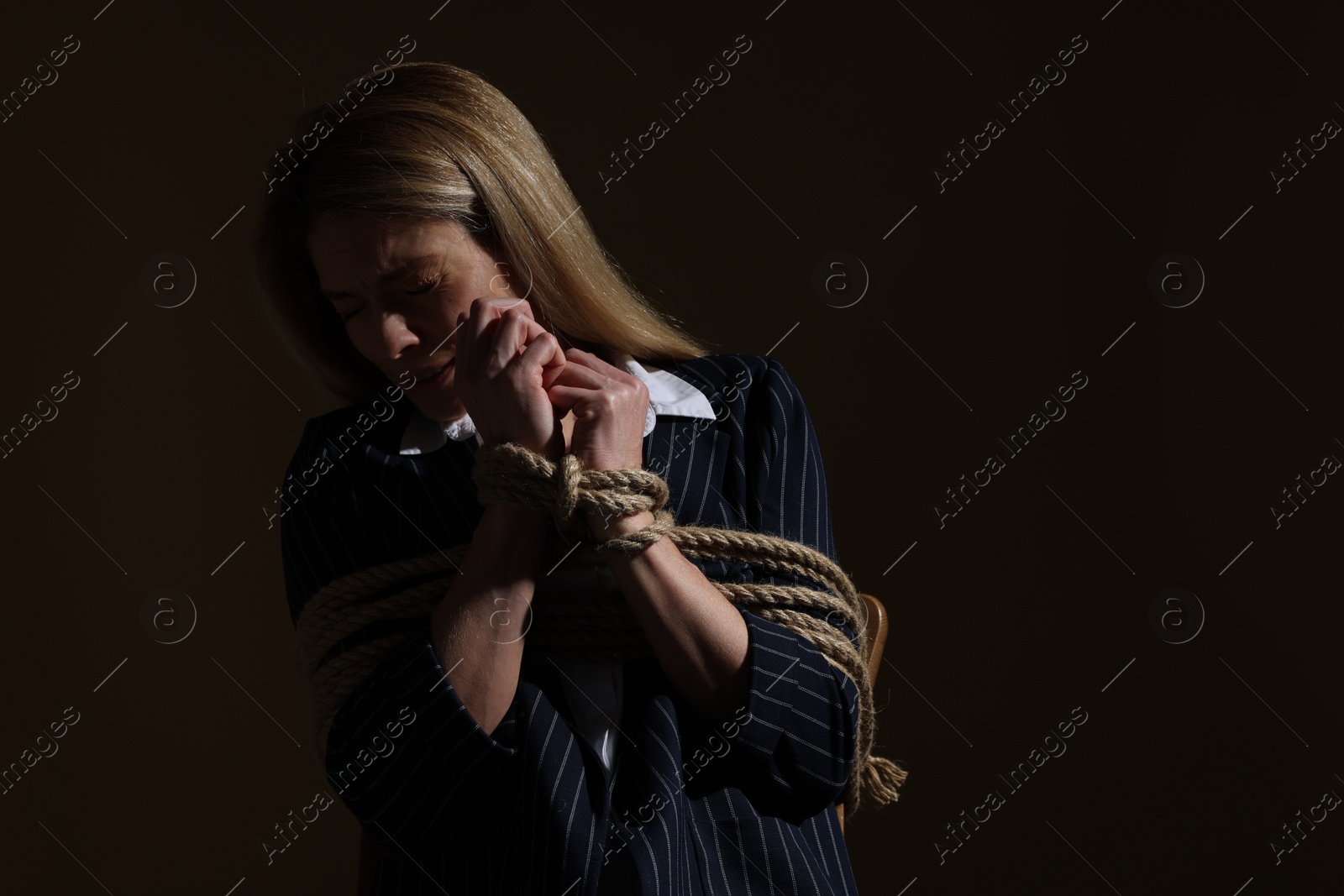 Photo of Woman tied up and taken hostage on dark background. Space for text