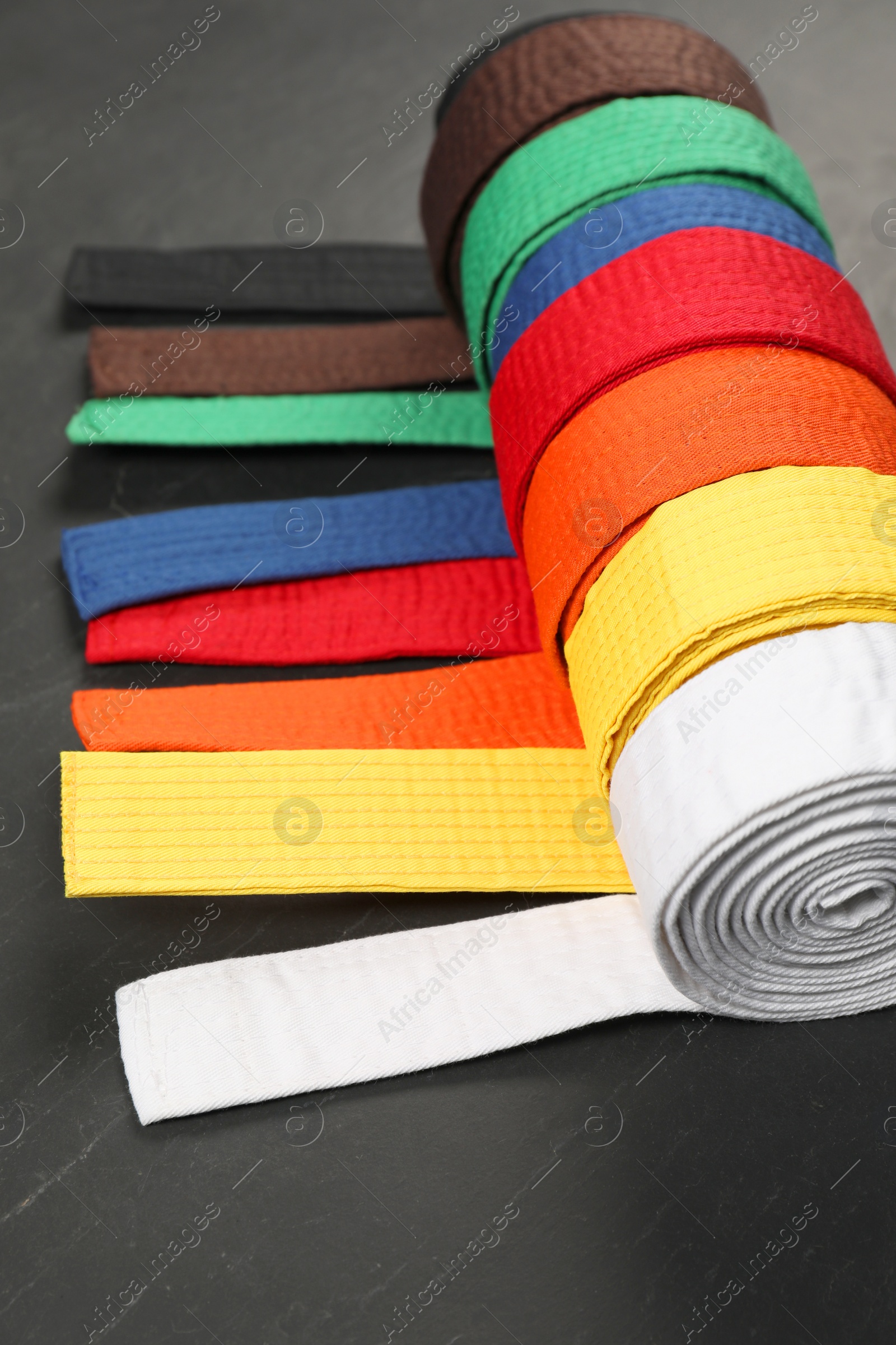 Photo of Colorful karate belts on gray background, closeup