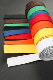 Photo of Colorful karate belts on gray background, closeup