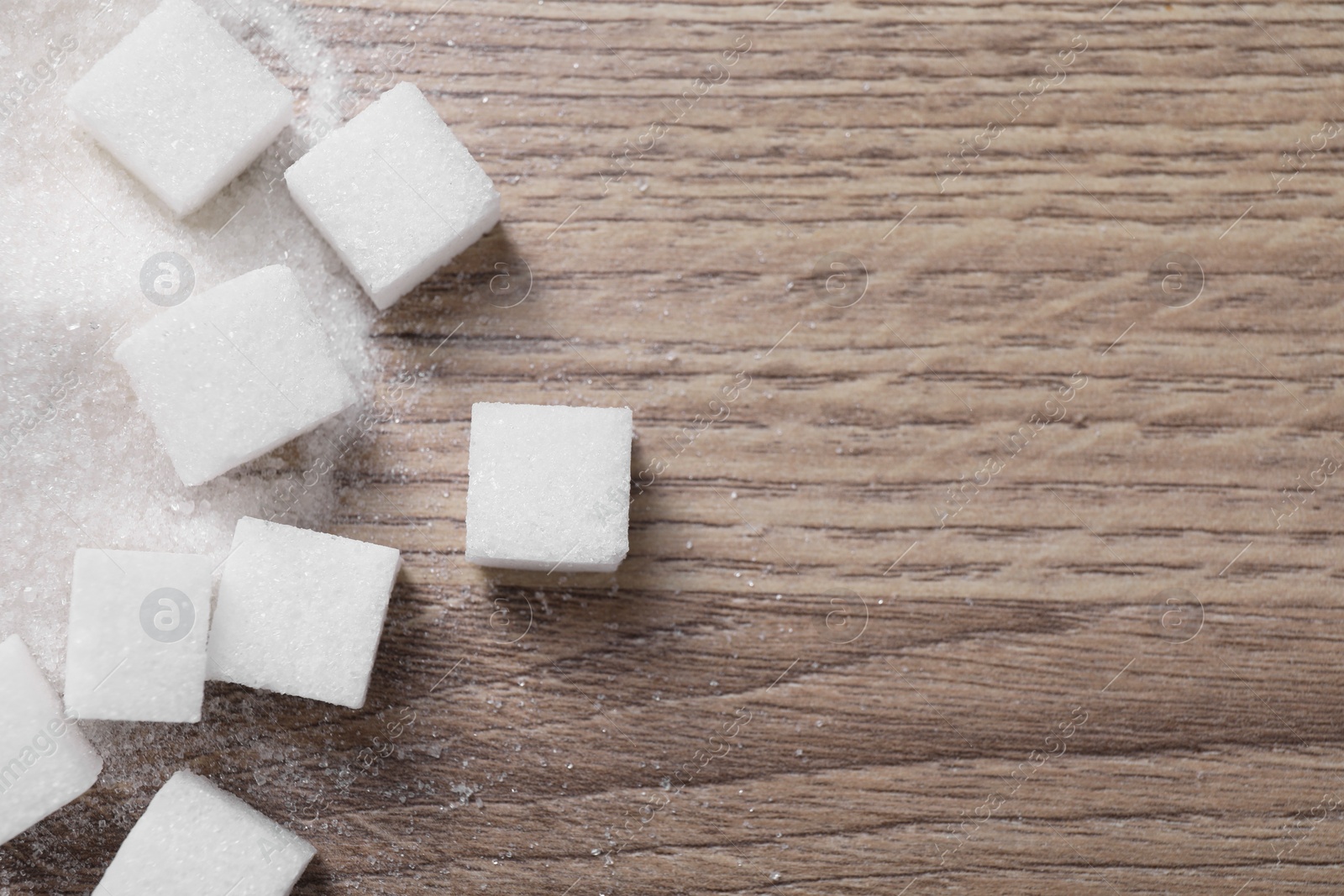 Photo of Different types of white sugar on wooden table, top view. Space for text