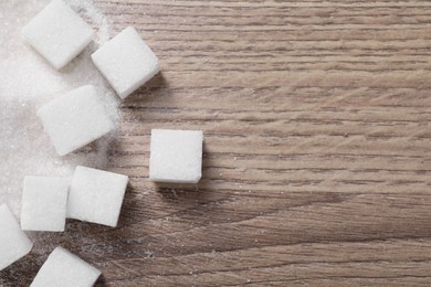 Different types of white sugar on wooden table, top view. Space for text