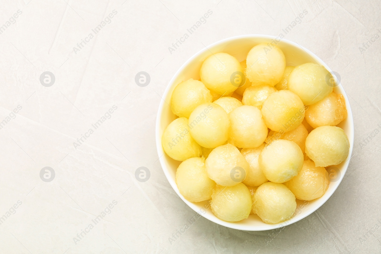 Photo of Bowl of melon balls on light table, top view. Space for text