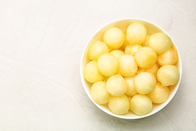 Photo of Bowl of melon balls on light table, top view. Space for text