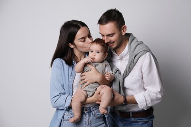 Photo of Happy family. Couple with their cute baby on grey background