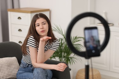 Photo of Teenage blogger sending air kiss to her subscribers while streaming at home