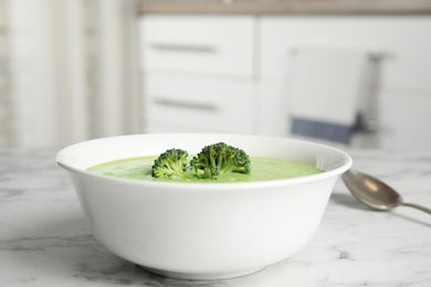 Photo of Delicious broccoli cream soup served on white marble table indoors