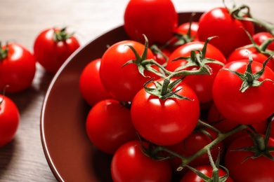 Photo of Plate with fresh cherry tomatoes on wooden background, closeup