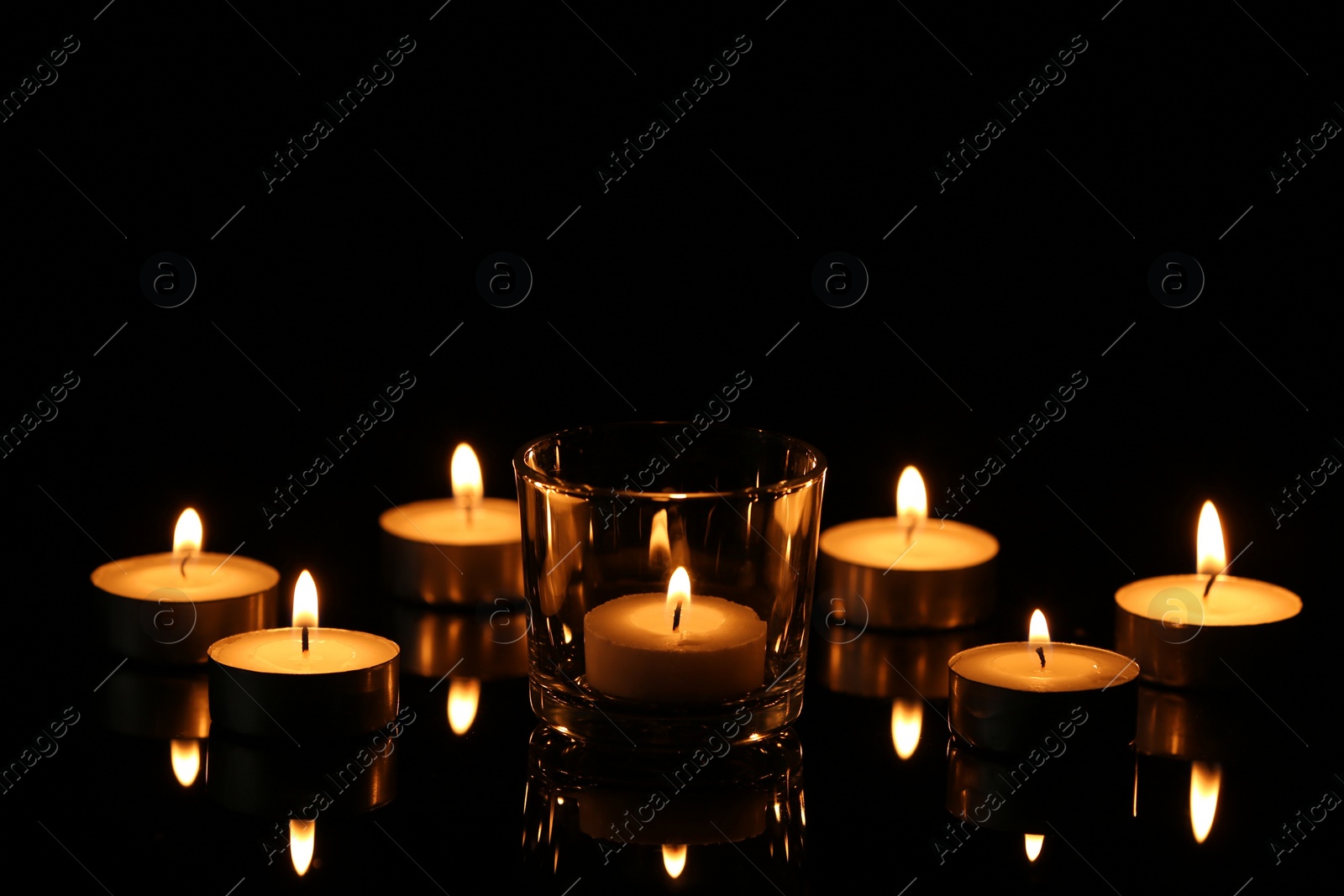 Photo of Burning small wax candles in darkness. Funeral symbol