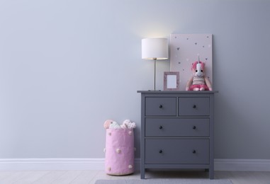 Modern grey chest of drawers near light wall in child room, space for text. Interior design