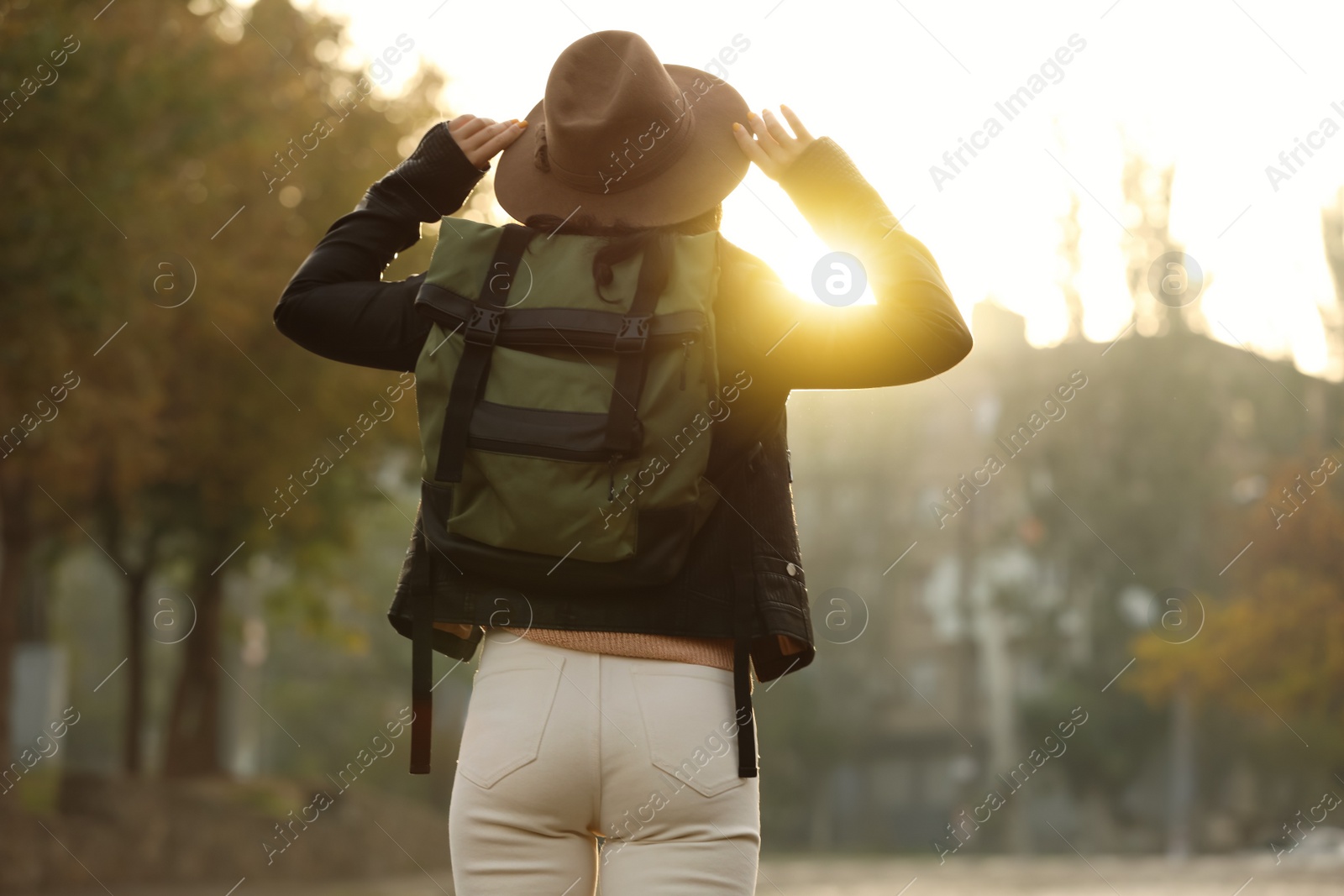 Photo of Traveler with backpack on city street, back view