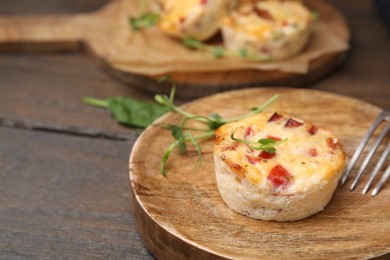 Delicious egg muffin with cheese and bacon on wooden table, closeup. Space for text