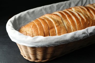 Photo of Slices of bread in basket on black table, closeup