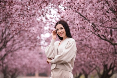 Photo of Pretty young woman in park with blooming trees. Spring look