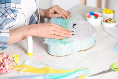 Woman decorating cardboard cloud at white wooden table, closeup. Pinata diy