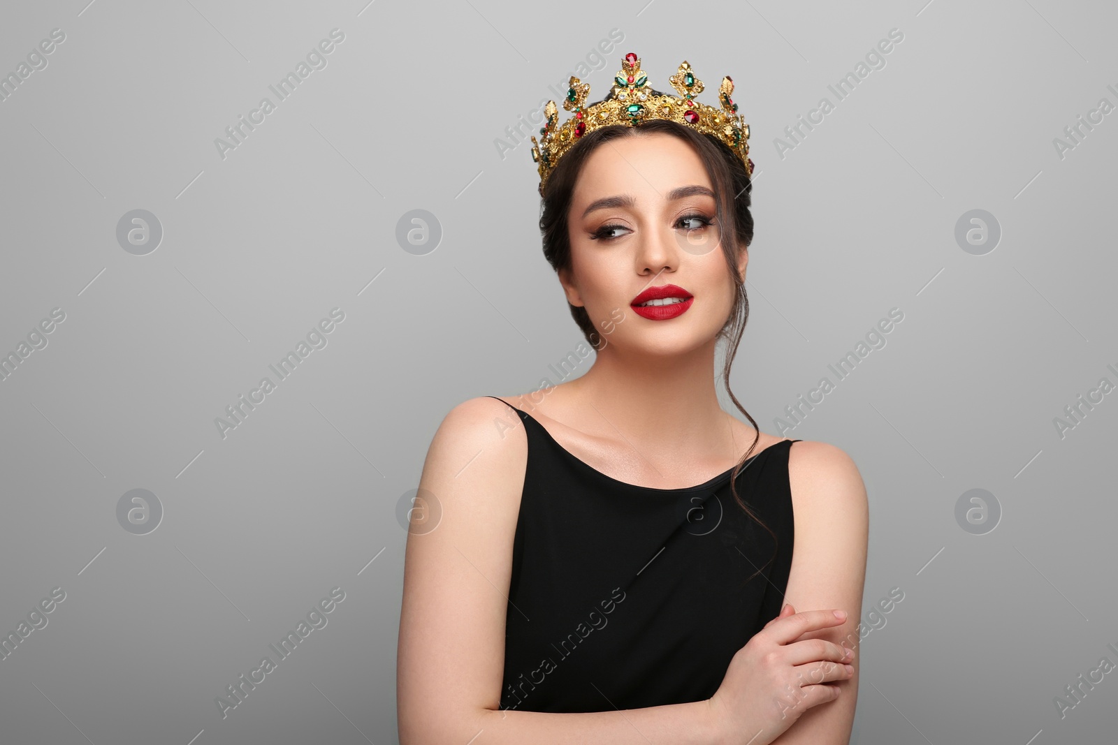 Photo of Beautiful young woman wearing luxurious crown on light grey background, space for text