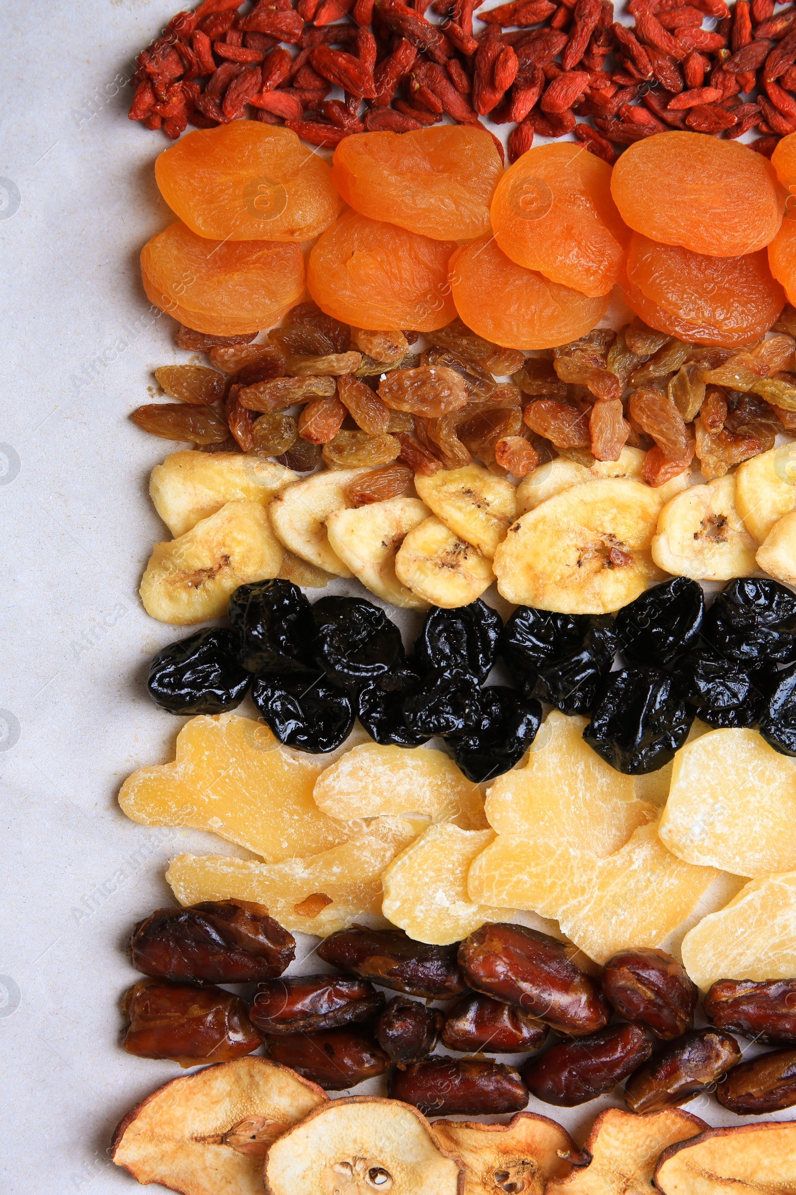 Photo of Different tasty dried fruits on paper, flat lay